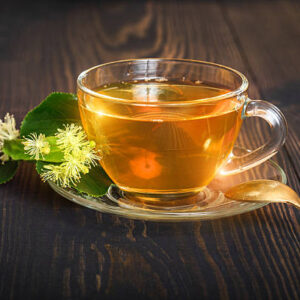 Linden tea on a wooden table in a glass cup. flower tea, herbal medicine.