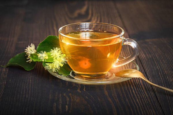 Linden tea on a wooden table in a glass cup. flower tea, herbal medicine.